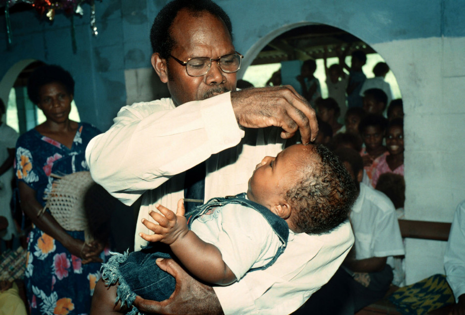 Vanuatu, Tanna Island, 1999On the island of Tanna in Vanuatu a cargo cult still survives worshipping John Frum.On John Frum Day worshipers dress in USA military uniforms,raise the US flag, and parade marching with bamboo rifles.Photo shows a Christian baptism service in a church near Sulpher Bay where missionaries are encroaching on the John Frum worshippers.Vanuatu, L'Óle Tanna, 1999Sur l'Óle de Tanna ‡ Vanuatu un cargo de lÈgende existe toujours en mÈmoire ‡ John Frum.Le jour de John Frum, les fidËles s'habillent en tenue militaire de l'armÈe amÈricaine, ils hissent le drapeau, et font des parades avec des carabines en bambou. La photo montre la cÈrÈmonie d'un baptÍme chrÈtien dans une Èglise prËs de Sulpher Bay o˘ des missionaires empiËtent le terrain des fidËles de John Frum.Steven Siewert / Agence VU