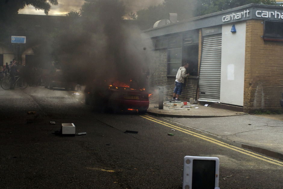 England, London, 08 August 2011Mare Street.Burning vehicle in front of Carhartt clothes warehouse on street adjacent to Mare Street, man looks inside.Angleterre, Londres, 08 ao˚t 2011Mare Street.Une voiture en feu devant un entrepÙt de vÍtements Carhartt, dans une rue adjacente ‡ Mare Street. Un homme regarde ‡ l'intÈrieur.Michael Grieve / Agence VU