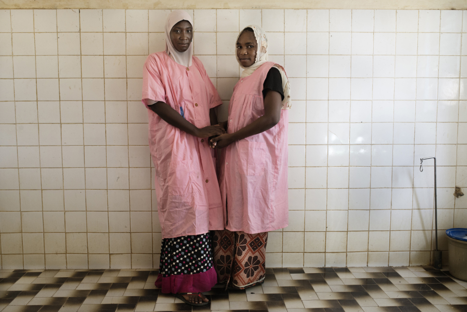 Niger, Zinder, Kantché, June 25th 2016In the Kantché maternity ward, Souleye Fati Harouna (in the left), 28 years old, and Adisa Moustapha, 27 years old, midwives, pose in front of the delivery room. They help about sixty women per month to give birth, although the majority give birth to their child at home.With almost 7,5 children per woman, Niger has the world's highest natality rate.Niger, Zinder, Kantché, 25 juin 2016Dans la maternité de Kantché, Souleye Fati Harouna (g), 28 ans et Adisa Moustapha, 27 ans, sages-femmes posent dans la salle d'acouchement. Elles accouchent une soixantaine de femmes par mois bien que la plupart des femmes donnent naissance à leur enfant chez elles.Le Niger possède une des taux de natalité  les plus élévé  au monde avec près de 7,5 enfants par femme.Michaël Zumstein / Agence VU