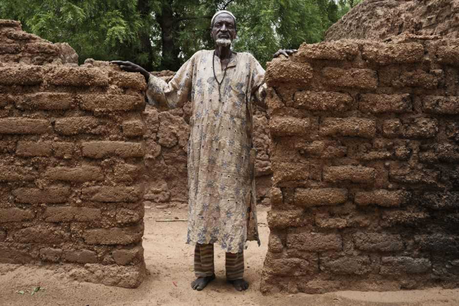 Niger, Zinder, Al Dawa, June 23rd 2016Abou Moussa, 65 years old, in front of his hut, in Al Dawa.Because his field was to small to feed his family, he went in Algeria to work, but he didn't succeed to find a job and has been deported. He contracts a 120 000 CFA's debt.Niger, Zinder, El Dawa, 23 juin 2016Dans le village d'El Dawa, Abou Moussa, 65 ans, pose à l'entrée d'une des case du village. Possédant un champ trop petit pour nourrir sa famille, il est parti travailler en Agérie mais expulsé du pays sans avoir réussi à travailler il a contracté une dette de 120 000 CFA.Michaël Zumstein / Agence VU