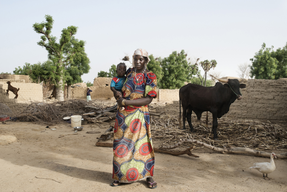 Niger, Zinder, Ragana, June 24th 2016Talatwa Lawali, 40 years old, poses with her child in front of the ox she bought with the money gathered from the begging in Algeria.Many inhabitants of the village goes, at their owns risks, to beg in Algeria. 14 people of the village died in the journey, in June 2016.Niger, Zinder, Ragana, 24 juin 2016Talatwa Lawali, 40 ans pose avec son enfant devant le boeuf qu'elle a pu acheter en allant mendier en Algérie. De nombreuses habitantes du village de Ragana partent vers l'Algérie pour aller mendier. 14 personnes de ce village sont mortes sur le trajet en juin 2016.Michaël Zumstein / Agence VU