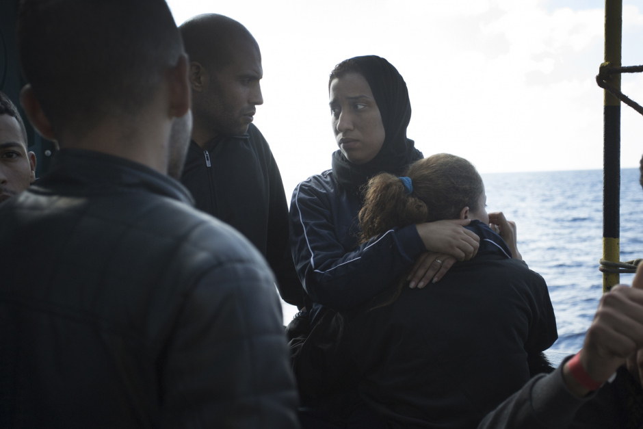 Mediterranean Sea, October 18th, 2017Rajaa, 27 years old (on the right), the day after the rescue, talks with other refugees helding her friend Hasna in her arms. Rajaa is Maroccan and had left her country two years ago following the economic crisis. She went to find fortune in Lybia with her childhood friend Hasna. "But, in Lybia, there is no life : militias make life impossible to people We can't go buying some bred without being arrested and getting robbed some money, they can kill you for nothing. In addition, I was working as hairdresser and I earned very few. We had escaped murder but we have seen so many people getting shot in front of our eyes.There were explosions everywhere, somtimes we didn't eat for two day, you don't know if you're gonna live or not, so you don't care about anything... We just wanted to have a simple life, without being afraid of dying every night. So we decided to take the boat. Everybody talk about these boats... We got into it. We saw this mother with her two daughters. I cried, because they are boats of death...But if she leave, even with her little girls, if we are gone, if I left my 6-year-old daughter and left her to my mother, it's because we don't have other choice... We leave our families, our country, everything. Because life over there is just not possible anymore..."Mer Méditerranée, 18 octobre 2017Rajaa, 27 ans (à droite) le lendemain du sauvetage, parle avec d’autres réfugiés en serrant son amie Hasna dans ses bras.Rajaa est marocaine et a quitté son pays il y a deux ans suite à la crise économique. Elle est allée chercher fortune en Libye avec son amie d’enfance Hasna. “Mais en Libye il n’y a aucune vie : les milices rendent la vie impossible aux gens. On ne peut pas aller acheter du pain sans être arrêtées et se faire voler de l’argent, ils peuvent te tuer pour rien. En plus je travaillais comme coiffeuse et je gagnais très peu. On a échappé au meurtre mais on a vu tellement de gens se f