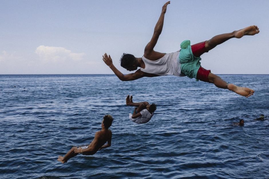 Cuba, Havana, July 8, 2017 - From the series “Sierra Maestra“. Teenagers jump in the sea in front of the Sierra Maestra's building.