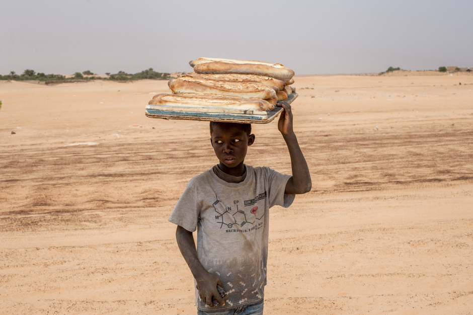 Mauritania, Adrar region, Chinguetti, March 31st 2018 A child selling bread. In Chinguetti, there are schools, but during the holidays or after classe, children help their families by working. Mauritanie, Adrar, Chinguetti, 31 mars 2018 Un enfant qui vend du pain. A Chinguetti, il y a des écoles, mais pendant les vacances ou après les cours les enfants aident leurs familles en travaillant. Ferhat Bouda / Agence VU