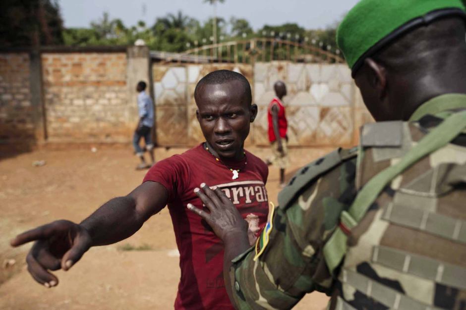 Central African Republic, Bangui, 22 January 2014At the Kilometre Point 13 (PK13), a Rwandan soldier of the African-led International Support Mission to the Central African Republic (MISCA) is trying to calm down an inhabitant of the Bégoua district, who is threatening a group of Muslims who have gathered in a house after the looting of their district.République Centrafricaine, Bangui, 22 Janvier 2014Au point kilométrique 13 (PK 13), un soldat de la Mission internationale de soutien à la Centrafrique (MISCA) Rawandaise tente de calmer un habitant du quartier de Bégoua, menacant un groupe de musulmans regroupés dans une maison, après le pillage et la destruction de leur quartier.Michael Zumstein / Agence VU