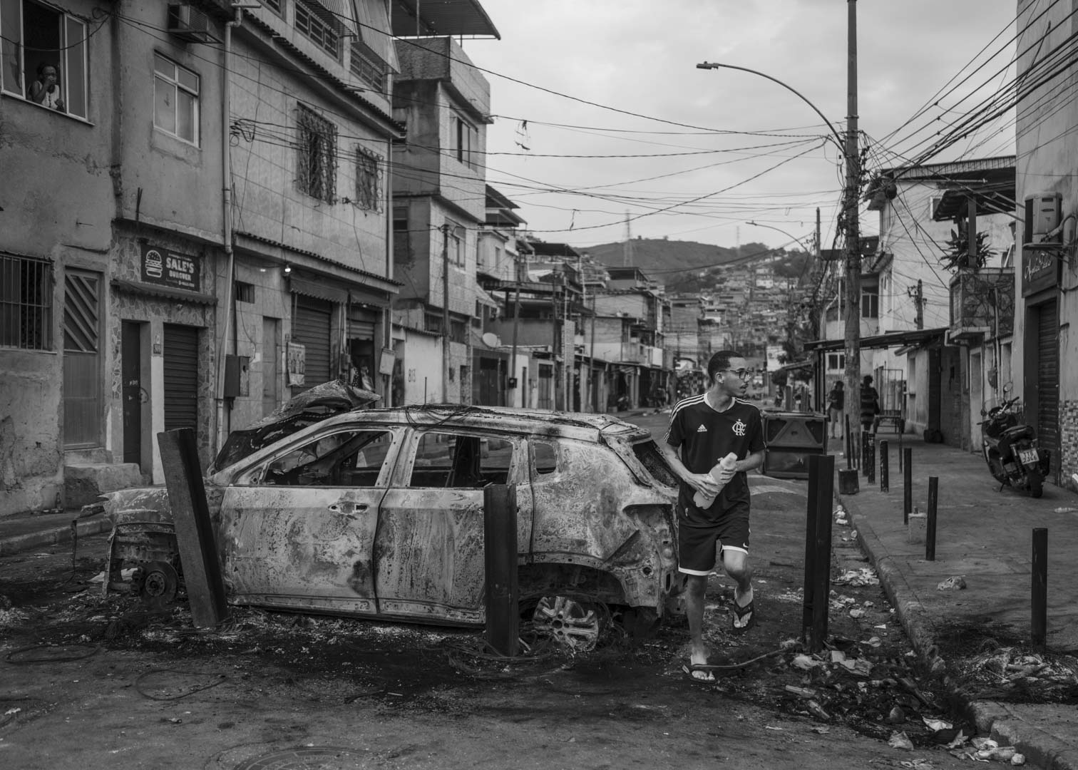 Brazil, Rio de Janeiro, 29 October 2025 - A man passes through a barricade of burned cars set up by drug traffickers to prevent armored vehicles belonging to special forces from entering Vila Cruzeiro, Complexo da Penha. The turbulent day follows the deadliest police operation in Rio de Janeiro's history, in which at least 126 people were killed.